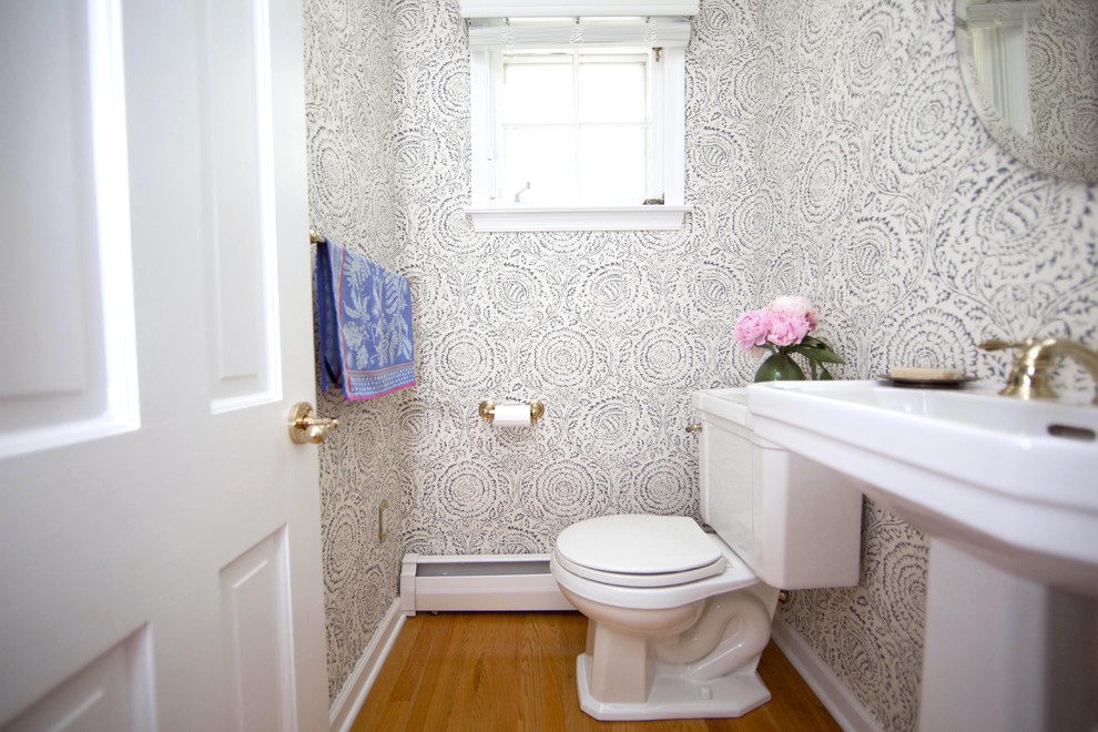 Example of a small transitional medium tone wood floor and brown floor powder room design in Philadelphia with a two-piece toilet, blue walls and a pedestal sink