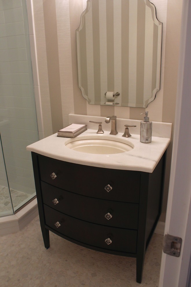 Cette image montre un WC et toilettes traditionnel en bois foncé de taille moyenne avec un plan de toilette en granite, un carrelage gris, un mur beige et un sol en marbre.