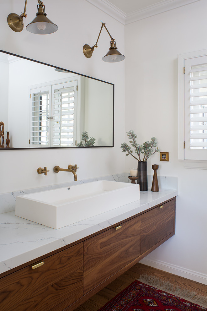 Medium sized contemporary cloakroom in Los Angeles with flat-panel cabinets, brown cabinets, a one-piece toilet, white tiles, porcelain tiles, white walls, a vessel sink, engineered stone worktops, brown floors, medium hardwood flooring and white worktops.