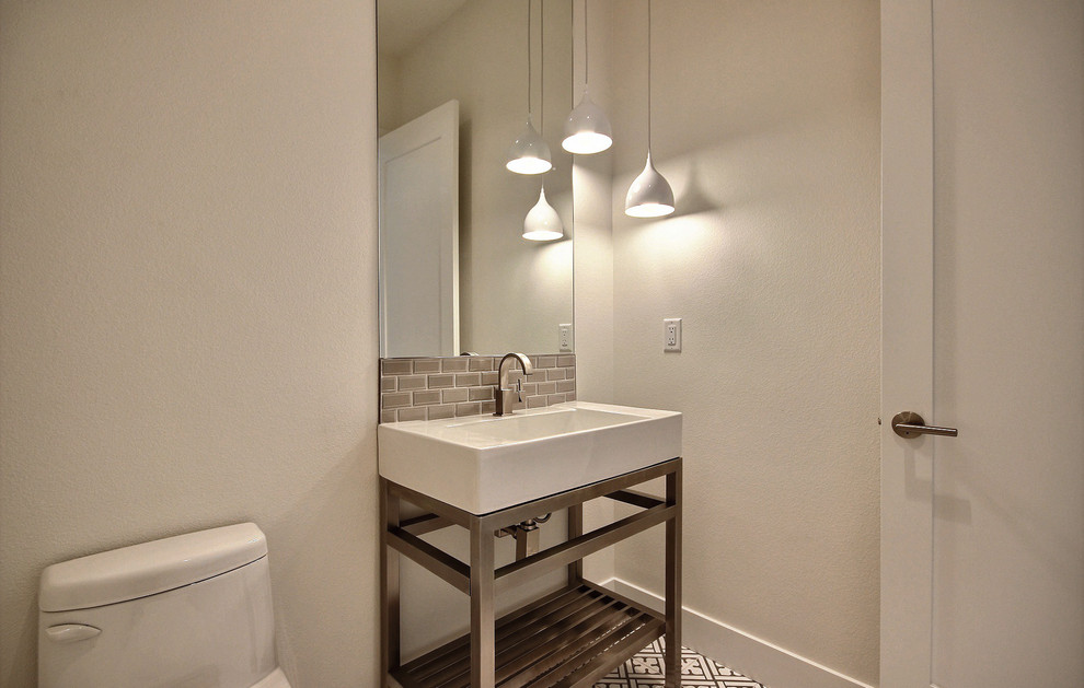 Пример оригинального дизайна: туалет среднего размера в стиле модернизм с открытыми фасадами, биде, серой плиткой, стеклянной плиткой, бежевыми стенами, полом из керамической плитки, раковиной с пьедесталом, разноцветным полом и белой столешницей