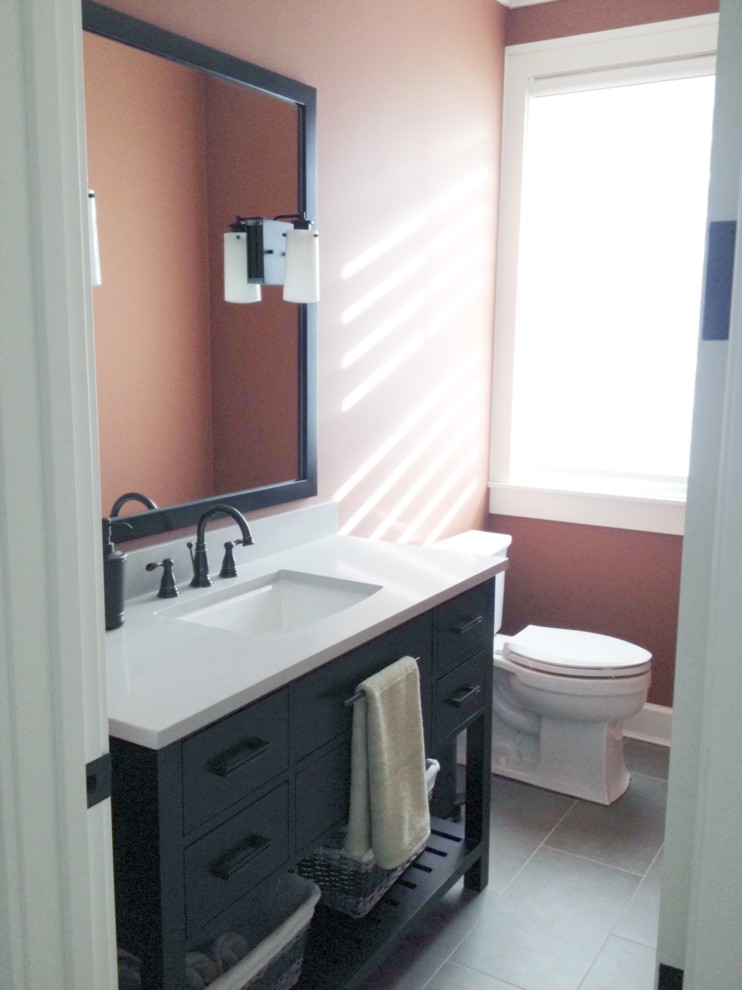 Medium sized farmhouse cloakroom in Grand Rapids with a submerged sink, flat-panel cabinets, dark wood cabinets, engineered stone worktops, a two-piece toilet, grey tiles, porcelain flooring and pink walls.