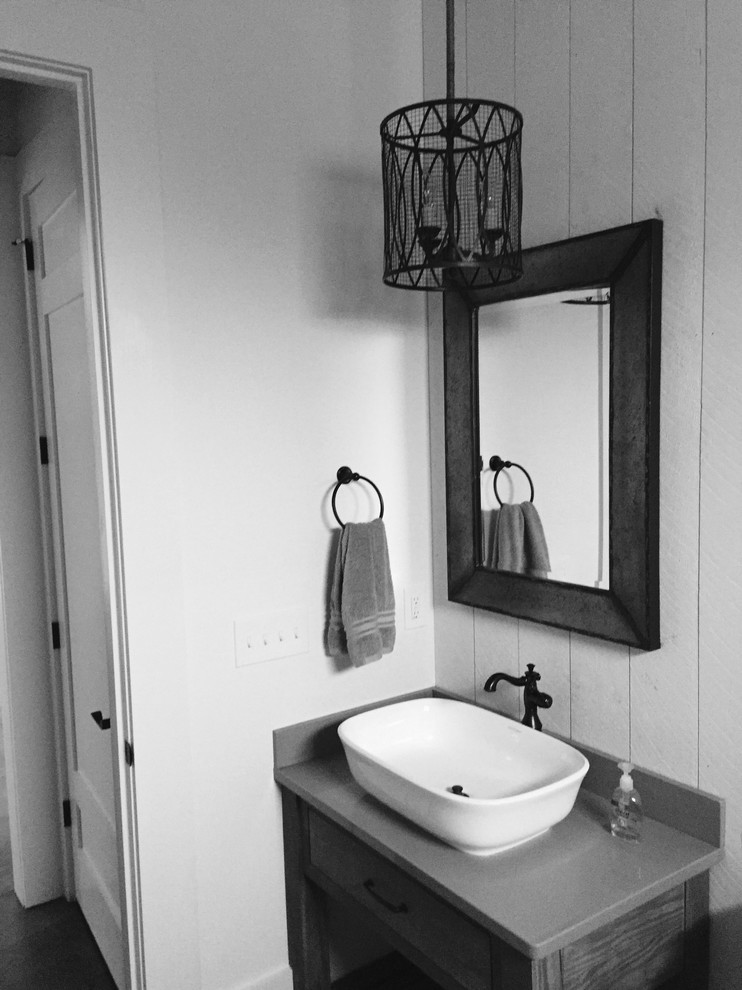 Bild på ett rustikt toalett, med öppna hyllor, grå skåp, vita väggar, ett väggmonterat handfat och bänkskiva i kvartsit