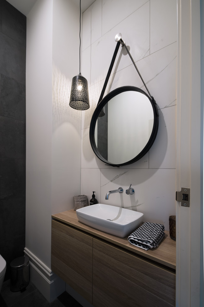 This is an example of a medium sized modern cloakroom in Melbourne with flat-panel cabinets, medium wood cabinets, grey tiles, white tiles, porcelain tiles, white walls, a vessel sink, wooden worktops and beige worktops.