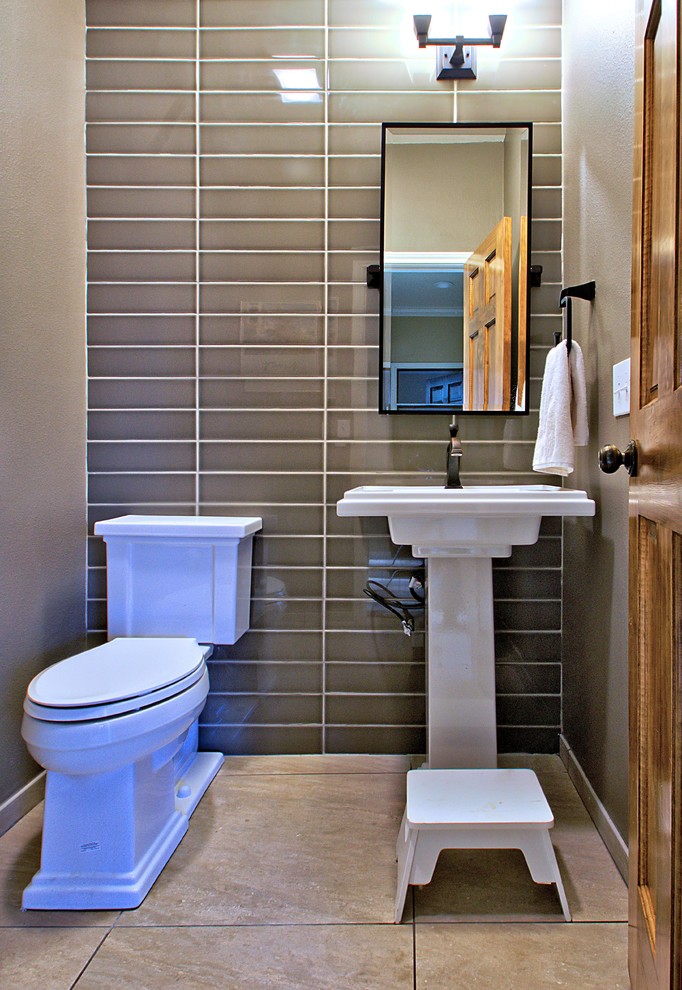 ダラスにある小さなトランジショナルスタイルのおしゃれなトイレ・洗面所 (ペデスタルシンク、分離型トイレ、茶色いタイル、セラミックタイル、茶色い壁、磁器タイルの床、照明) の写真