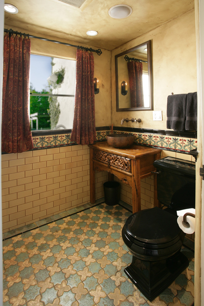 Cette photo montre un petit WC et toilettes méditerranéen en bois brun avec un placard en trompe-l'oeil, WC séparés, un carrelage multicolore, des carreaux de céramique, un mur jaune, un sol en carrelage de céramique, une vasque et un plan de toilette en bois.