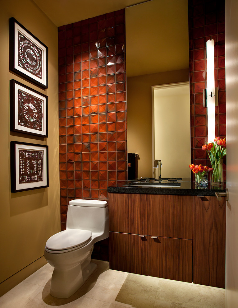 Foto på ett amerikanskt toalett, med ett undermonterad handfat, släta luckor, skåp i mörkt trä, orange kakel och en toalettstol med hel cisternkåpa