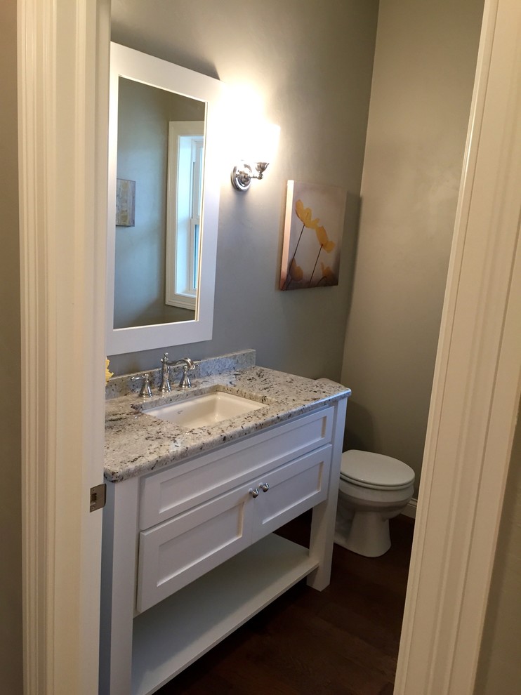 Immagine di un bagno di servizio american style di medie dimensioni con lavabo sottopiano, ante bianche, top in granito, pareti grigie e ante con riquadro incassato