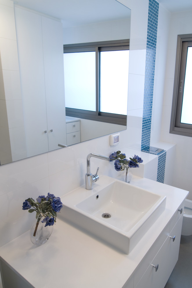 Réalisation d'un WC et toilettes design avec une vasque, un placard à porte plane, des portes de placard blanches et un carrelage bleu.