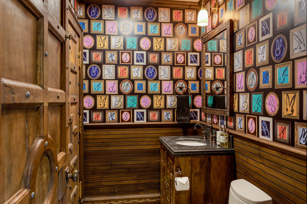 Immagine di un bagno di servizio etnico con ante in legno bruno, lavabo sottopiano e top nero