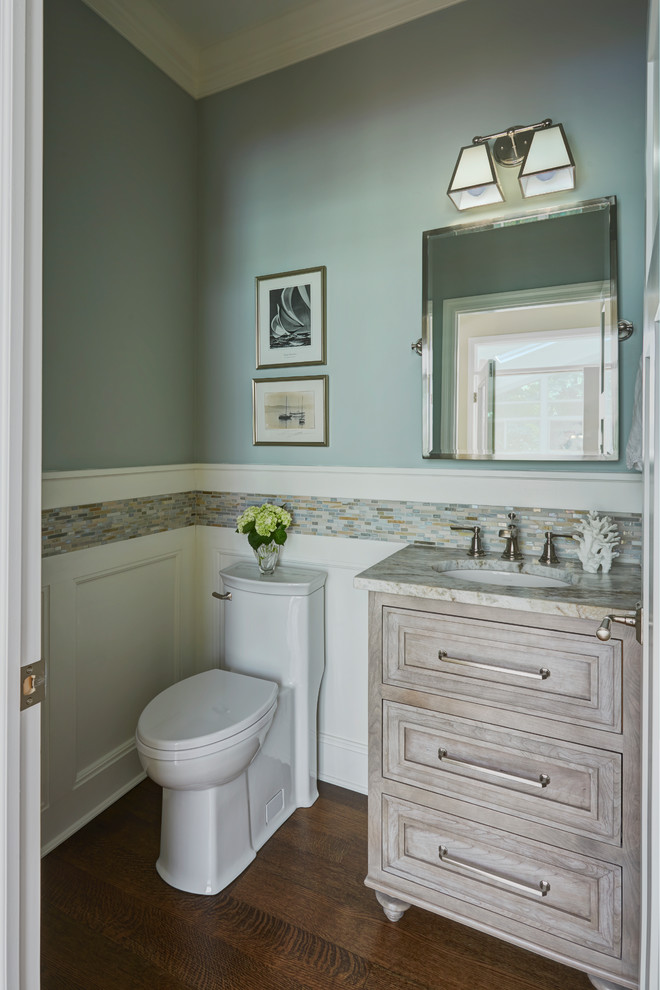 Kleine Klassische Gästetoilette mit verzierten Schränken, grauen Schränken, Toilette mit Aufsatzspülkasten, farbigen Fliesen, Glasfliesen, blauer Wandfarbe, braunem Holzboden, Unterbauwaschbecken, Laminat-Waschtisch und braunem Boden in Baltimore