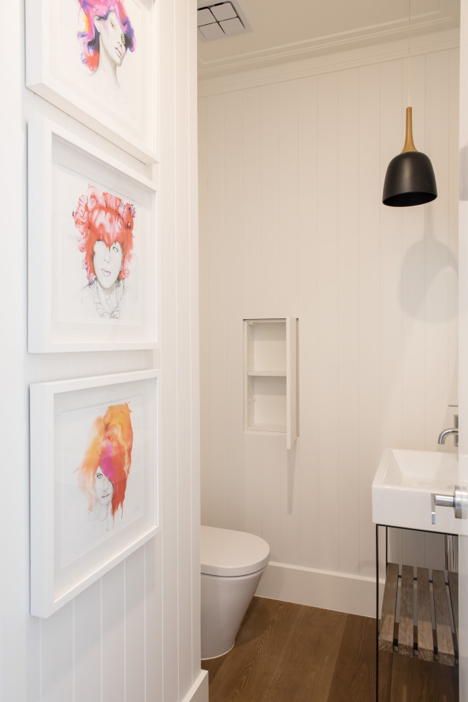 Geräumige Maritime Gästetoilette mit weißen Schränken, Toilette mit Aufsatzspülkasten, weißer Wandfarbe, braunem Holzboden, Waschtischkonsole und braunem Boden in Melbourne