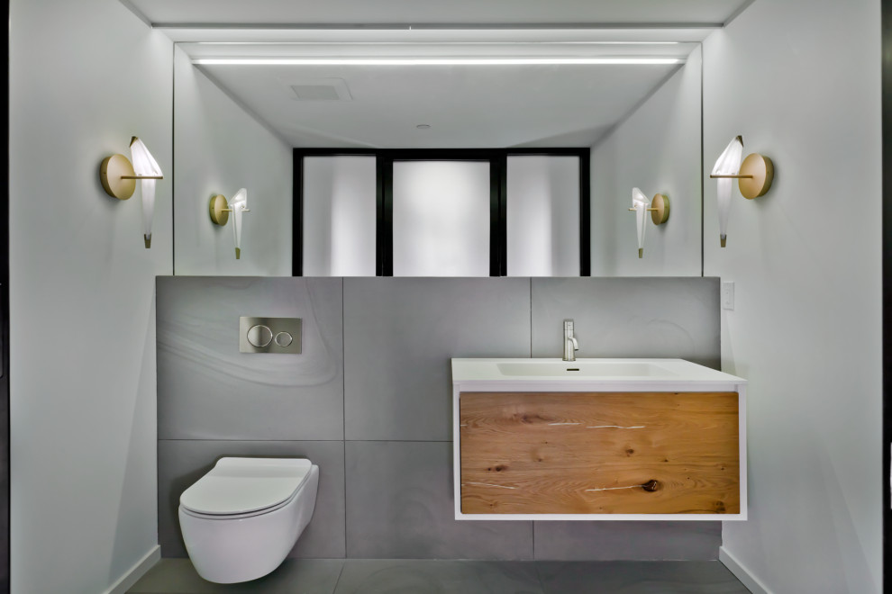 Idée de décoration pour un petit WC suspendu design en bois brun avec un placard à porte plane, un carrelage gris, des carreaux de porcelaine, un mur blanc, un sol en carrelage de porcelaine, un lavabo intégré, un plan de toilette en surface solide, un sol gris et un plan de toilette blanc.