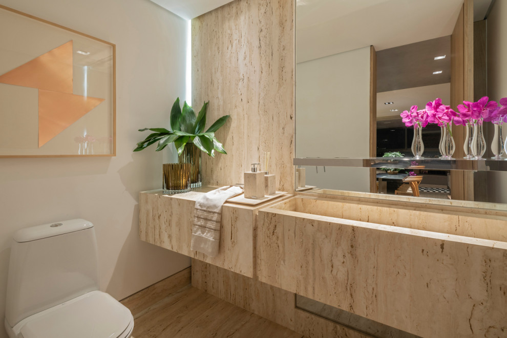 На фото: туалет в современном стиле с бежевой плиткой, плиткой из листового камня, белыми стенами, монолитной раковиной, бежевым полом и бежевой столешницей с