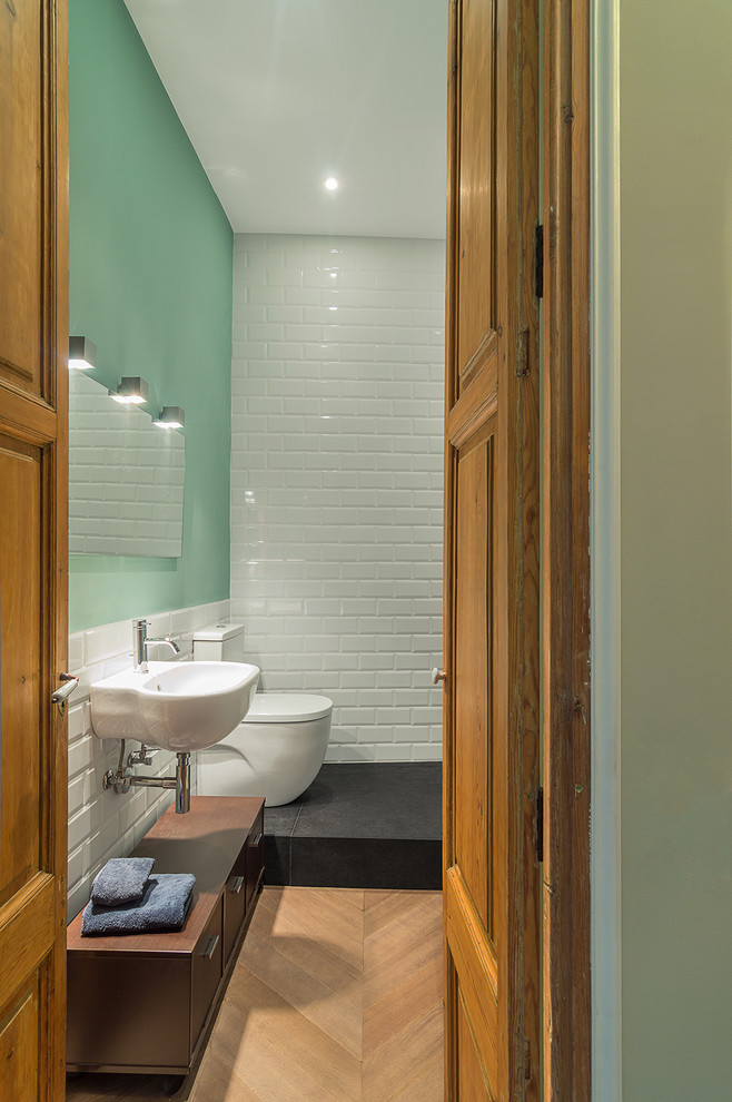 Esempio di un bagno di servizio design di medie dimensioni con ante lisce, ante in legno scuro, WC a due pezzi, pareti verdi, pavimento in legno massello medio e lavabo sospeso