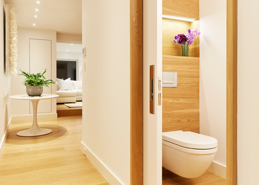 Aménagement d'un petit WC suspendu contemporain en bois vieilli avec un placard à porte plane, un mur blanc, parquet clair, une vasque et un plan de toilette en bois.