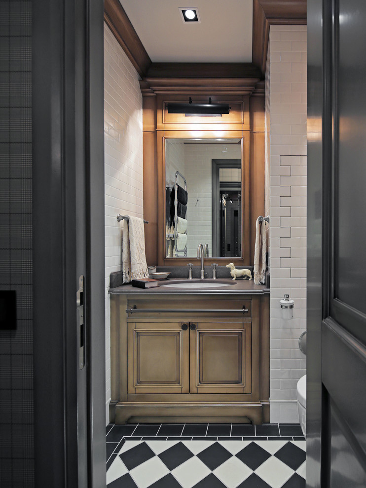 Klassisk inredning av ett toalett, med luckor med infälld panel, skåp i mellenmörkt trä, vit kakel, svart och vit kakel, ett undermonterad handfat och flerfärgat golv