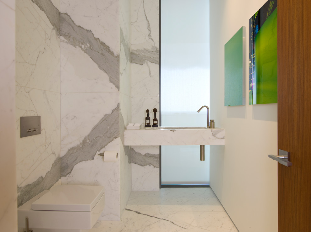 Immagine di un bagno di servizio minimal con WC sospeso, piastrelle bianche, piastrelle di marmo, pareti bianche, pavimento in marmo, lavabo integrato, top in marmo, pavimento bianco e top bianco