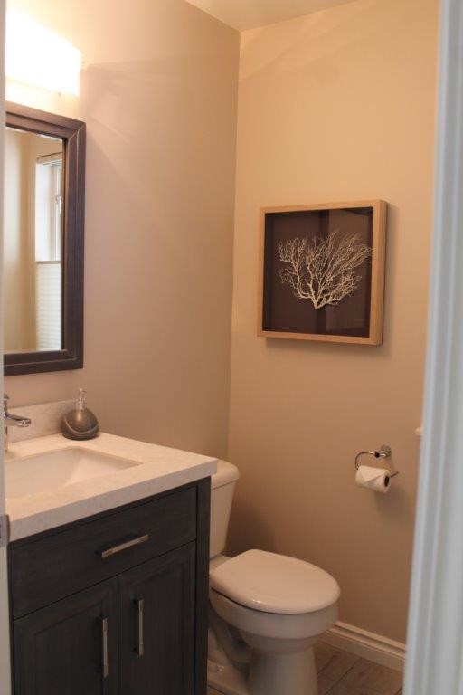 Immagine di un bagno di servizio minimal con ante lisce, ante in legno bruno, WC monopezzo, pareti beige e lavabo sottopiano