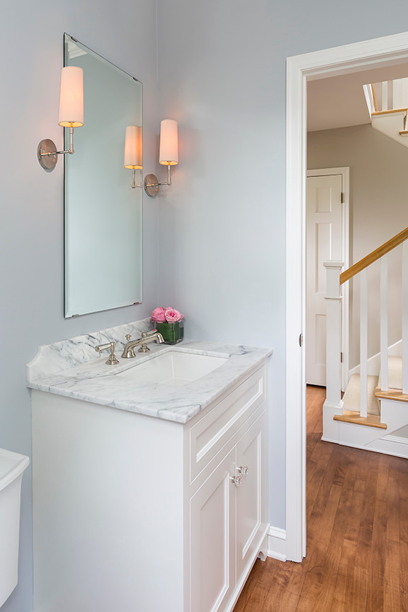Powder room - traditional medium tone wood floor powder room idea in Minneapolis with flat-panel cabinets, white cabinets, marble countertops, gray walls and white countertops