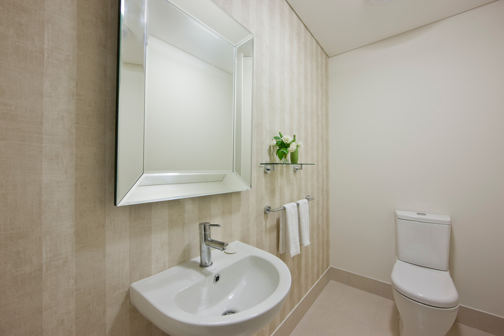 Inspiration pour un WC et toilettes minimaliste de taille moyenne avec WC à poser, un carrelage beige, un sol en carrelage de céramique, un lavabo suspendu et un mur beige.