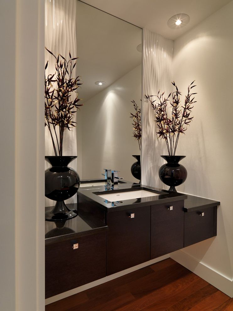 Example of a trendy powder room design in Vancouver with black countertops