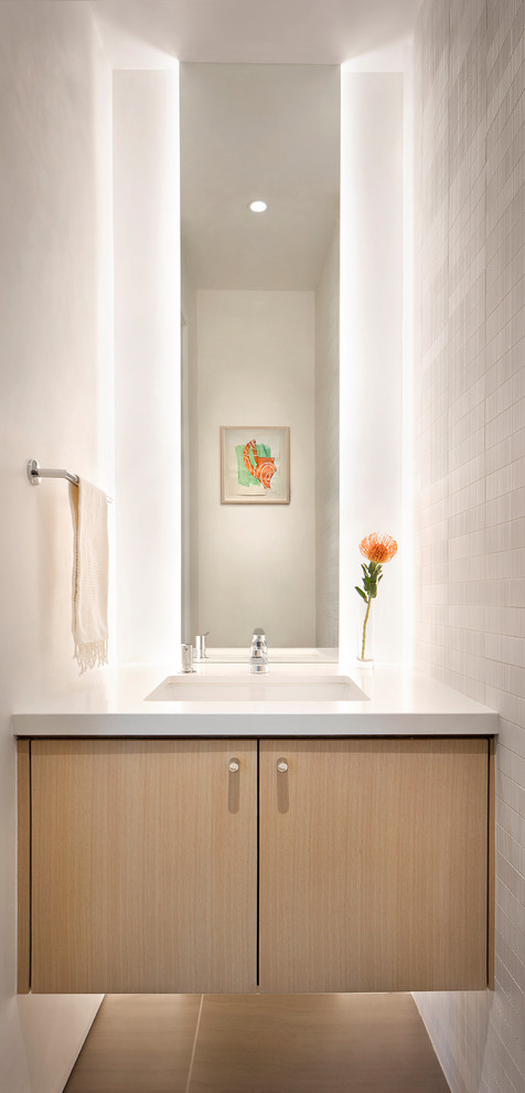 Cette photo montre un WC et toilettes scandinave en bois clair avec un placard à porte plane, un mur blanc, un lavabo encastré, un sol beige et un plan de toilette blanc.