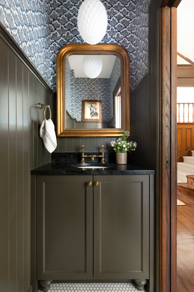 Inspiration for a timeless mosaic tile floor, white floor, wainscoting and wallpaper powder room remodel in Minneapolis with recessed-panel cabinets, green cabinets, blue walls, an undermount sink, black countertops and a freestanding vanity