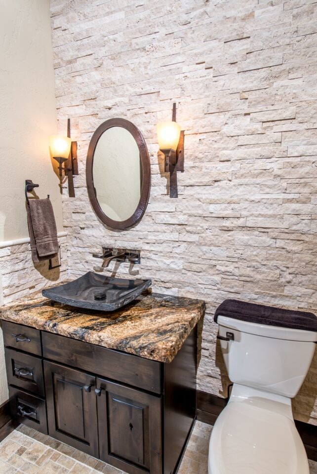 Large rustic cloakroom in Seattle with a vessel sink, raised-panel cabinets, dark wood cabinets, granite worktops, a one-piece toilet, beige tiles, stone tiles, beige walls and travertine flooring.