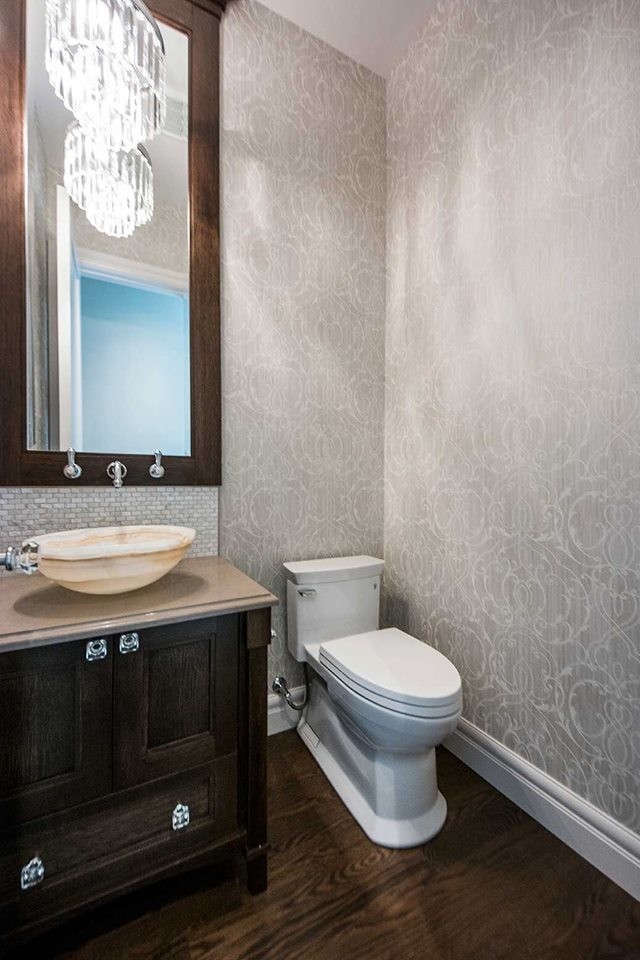 Exemple d'un WC et toilettes chic en bois foncé avec un placard à porte shaker, un carrelage gris, un carrelage en pâte de verre, un mur gris, parquet foncé, une vasque, un plan de toilette en granite et un sol marron.