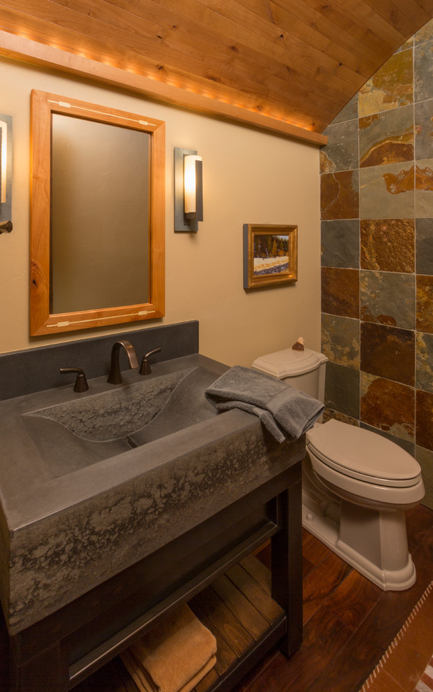 デンバーにあるラスティックスタイルのおしゃれなトイレ・洗面所 (一体型シンク、家具調キャビネット、濃色木目調キャビネット、マルチカラーのタイル、石タイル) の写真
