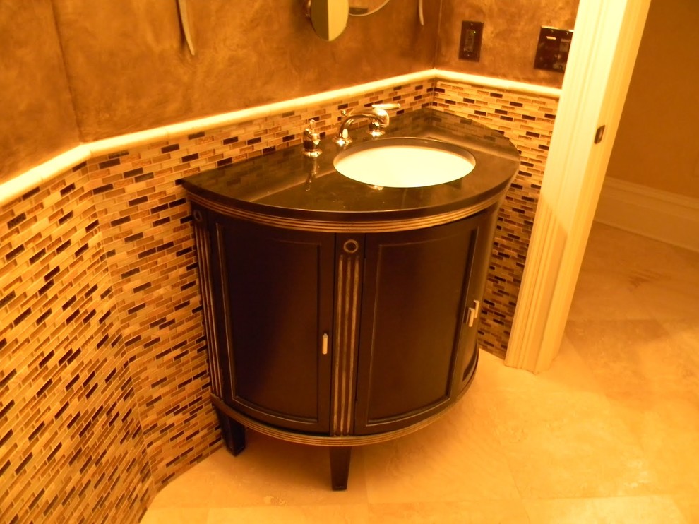 Photo of a small contemporary cloakroom in Atlanta with freestanding cabinets, dark wood cabinets, a one-piece toilet, multi-coloured tiles, glass tiles, brown walls, limestone flooring, a submerged sink and beige floors.