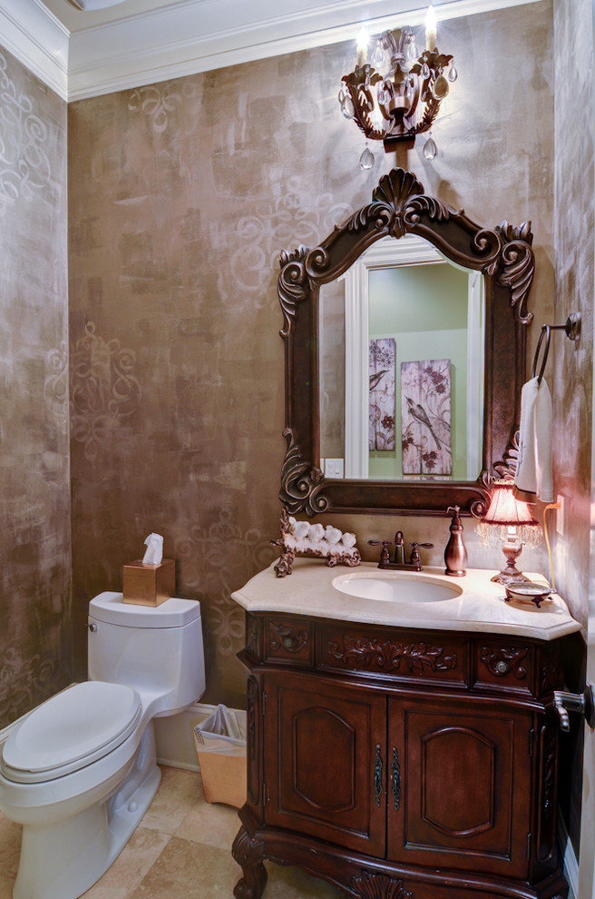 Inredning av ett klassiskt mellanstort toalett, med ett undermonterad handfat, möbel-liknande, skåp i mörkt trä, marmorbänkskiva, en toalettstol med hel cisternkåpa, beige kakel, travertin golv och bruna väggar