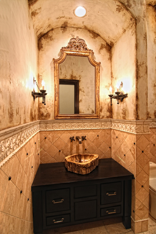 Photo of a large mediterranean cloakroom in Austin with freestanding cabinets, brown cabinets, a one-piece toilet, travertine flooring, a vessel sink, wooden worktops, multi-coloured tiles, stone tiles, multi-coloured walls and multi-coloured floors.