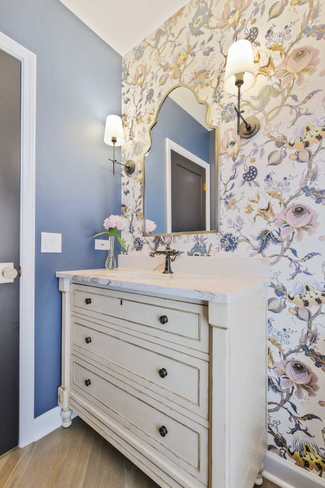 Transitional medium tone wood floor and brown floor powder room photo in Chicago with distressed cabinets, blue walls, an undermount sink and white countertops