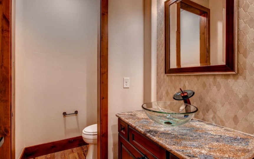 Foto di un bagno di servizio tradizionale con lavabo a bacinella, ante con riquadro incassato, ante in legno bruno e pareti beige
