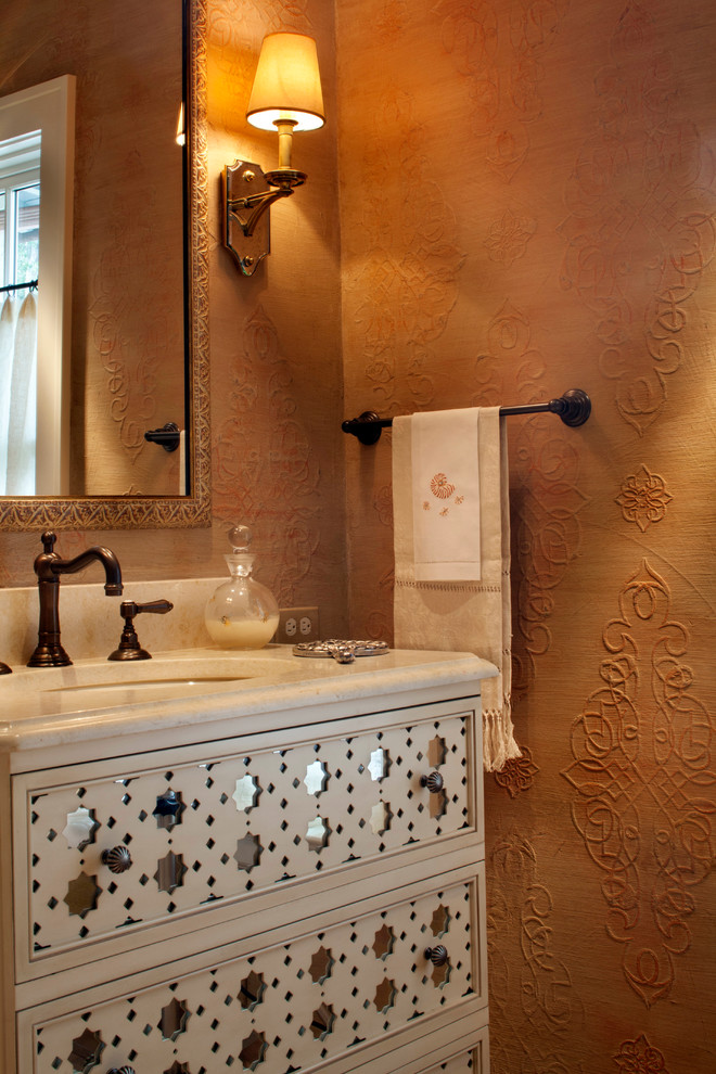 ジャクソンビルにある地中海スタイルのおしゃれなトイレ・洗面所 (白いキャビネット、オレンジの壁、アンダーカウンター洗面器、ライムストーンの洗面台、白い洗面カウンター、独立型洗面台) の写真