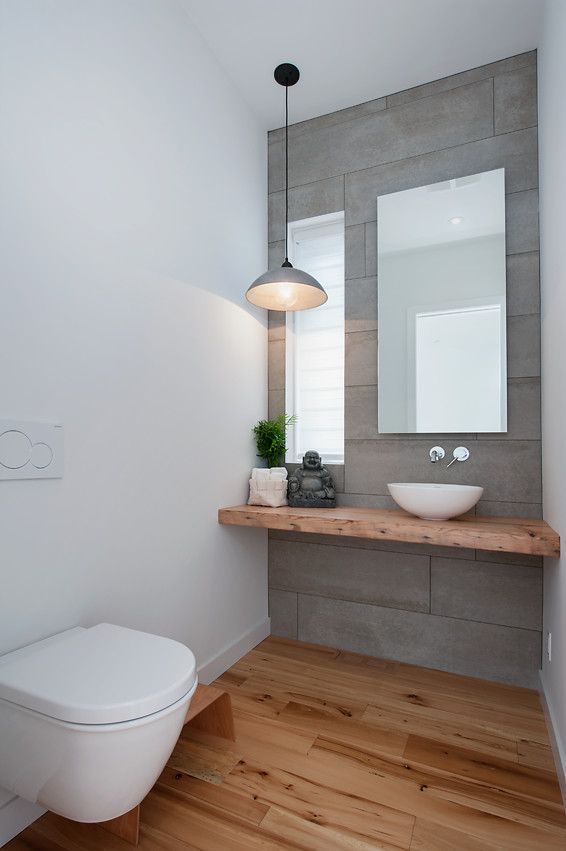 Exemple d'un grand WC suspendu tendance avec une vasque, un plan de toilette en bois, un carrelage gris, un mur blanc, parquet clair, des carreaux de béton et un plan de toilette marron.