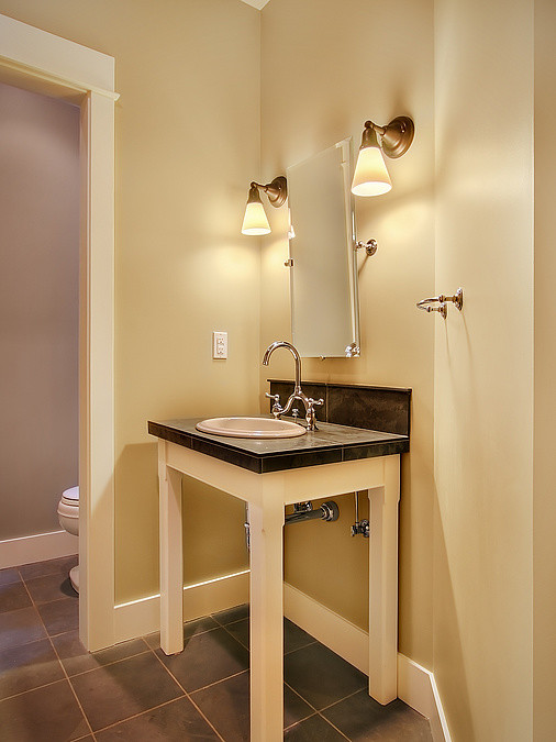 Inspiration pour un WC et toilettes traditionnel de taille moyenne avec un lavabo posé, WC à poser, un carrelage marron et un mur jaune.