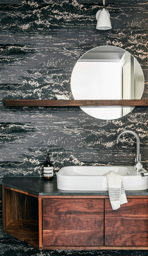 Example of a small trendy wallpaper powder room design in San Francisco with flat-panel cabinets, medium tone wood cabinets, a vessel sink, blue walls, granite countertops, black countertops and a floating vanity