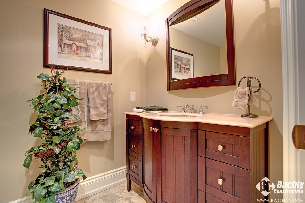 Imagen de aseo tradicional de tamaño medio con lavabo bajoencimera, armarios tipo mueble, puertas de armario de madera en tonos medios y paredes beige