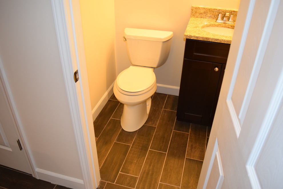 Cette image montre un petit WC et toilettes traditionnel en bois foncé avec un placard avec porte à panneau encastré, WC séparés, un mur beige, parquet foncé, un lavabo encastré, un plan de toilette en granite, un sol marron et un plan de toilette marron.