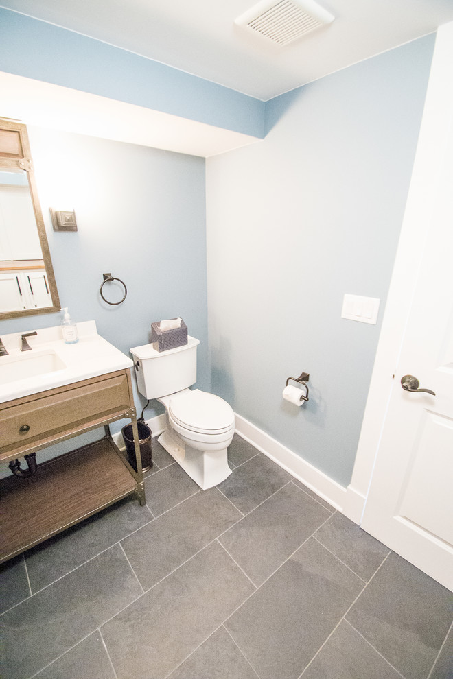 Ispirazione per un bagno di servizio classico di medie dimensioni con pareti blu, ante con bugna sagomata, ante in legno scuro, WC monopezzo, pavimento in ardesia, lavabo sottopiano e top in superficie solida