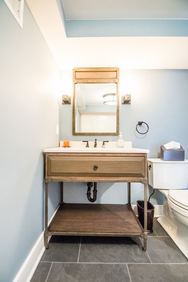 Foto di un bagno di servizio tradizionale di medie dimensioni con pareti blu, ante con bugna sagomata, ante in legno scuro, WC monopezzo, pavimento in ardesia, lavabo sottopiano e top in superficie solida