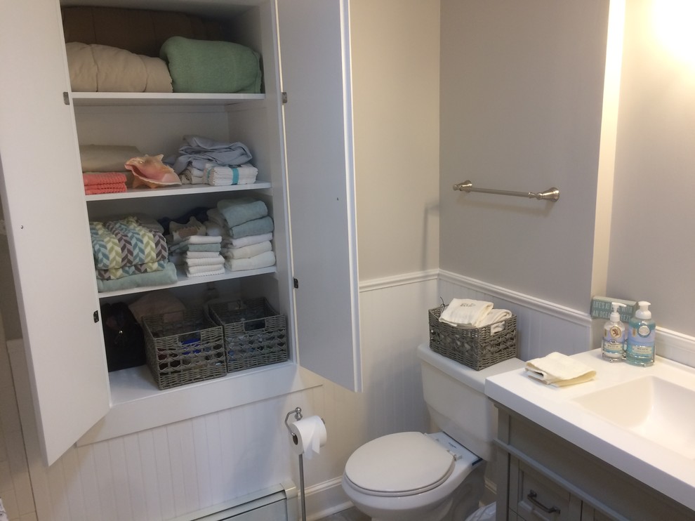 Small traditional cloakroom in Boston with recessed-panel cabinets, grey cabinets, a two-piece toilet, grey walls, porcelain flooring, an integrated sink, solid surface worktops and grey floors.