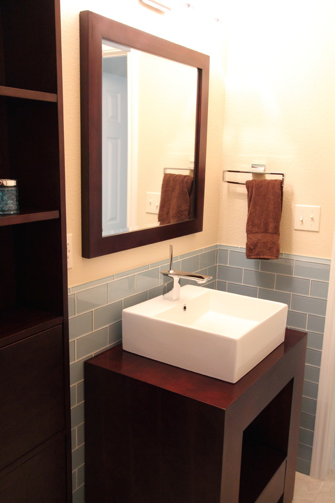 Moderne Gästetoilette mit Aufsatzwaschbecken, offenen Schränken, dunklen Holzschränken, Waschtisch aus Holz, Toilette mit Aufsatzspülkasten, blauen Fliesen, Metrofliesen, beiger Wandfarbe und Keramikboden in Houston