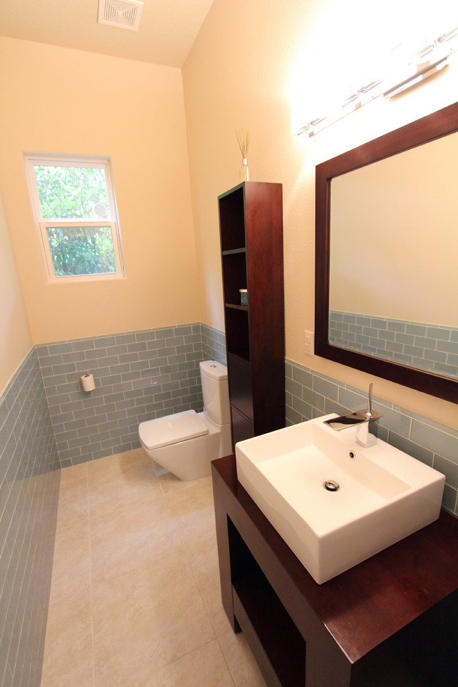 Inspiration pour un WC et toilettes minimaliste en bois foncé avec une vasque, un placard sans porte, un plan de toilette en bois, WC à poser, un carrelage bleu, un carrelage métro, un mur beige et un sol en carrelage de céramique.