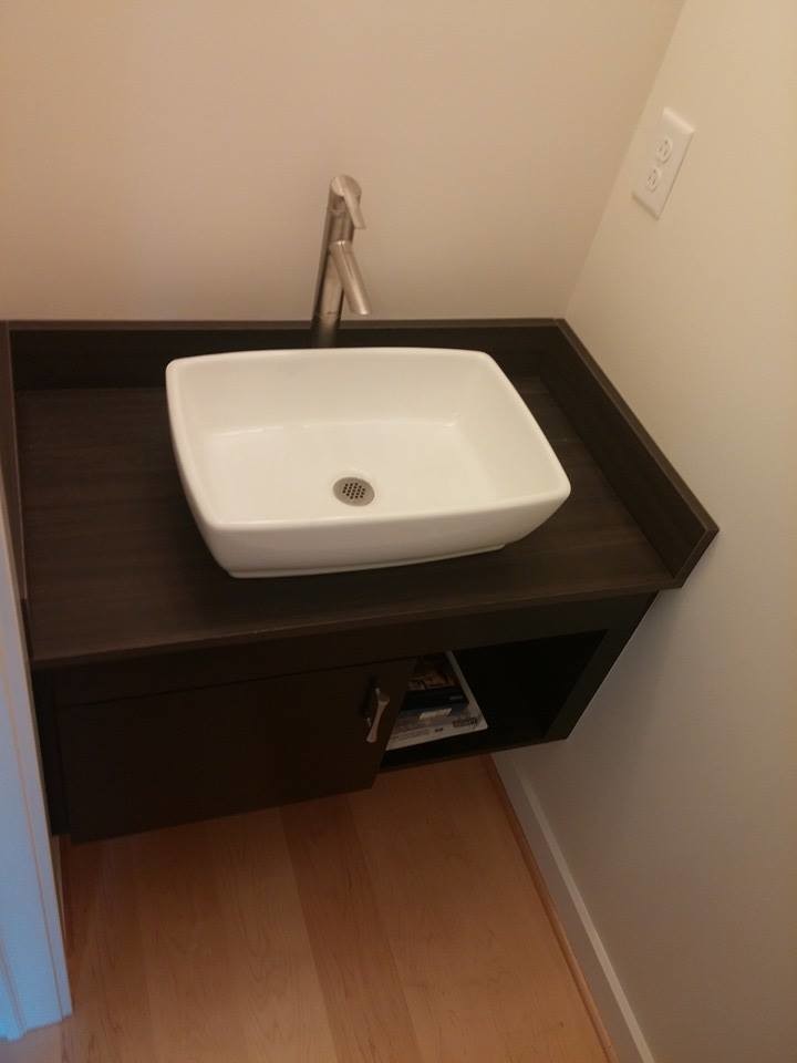 Foto på ett litet funkis toalett, med möbel-liknande, skåp i mörkt trä, en toalettstol med hel cisternkåpa, beige väggar, ett fristående handfat och träbänkskiva