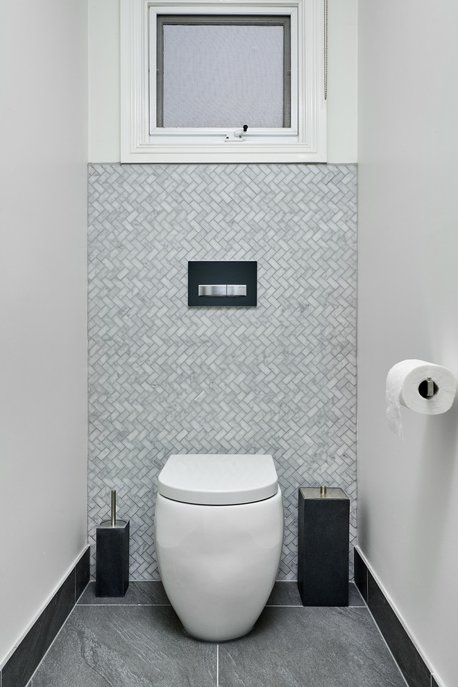 Esempio di un bagno di servizio minimalista con WC sospeso, piastrelle a mosaico, pareti bianche, pavimento in gres porcellanato e pavimento grigio