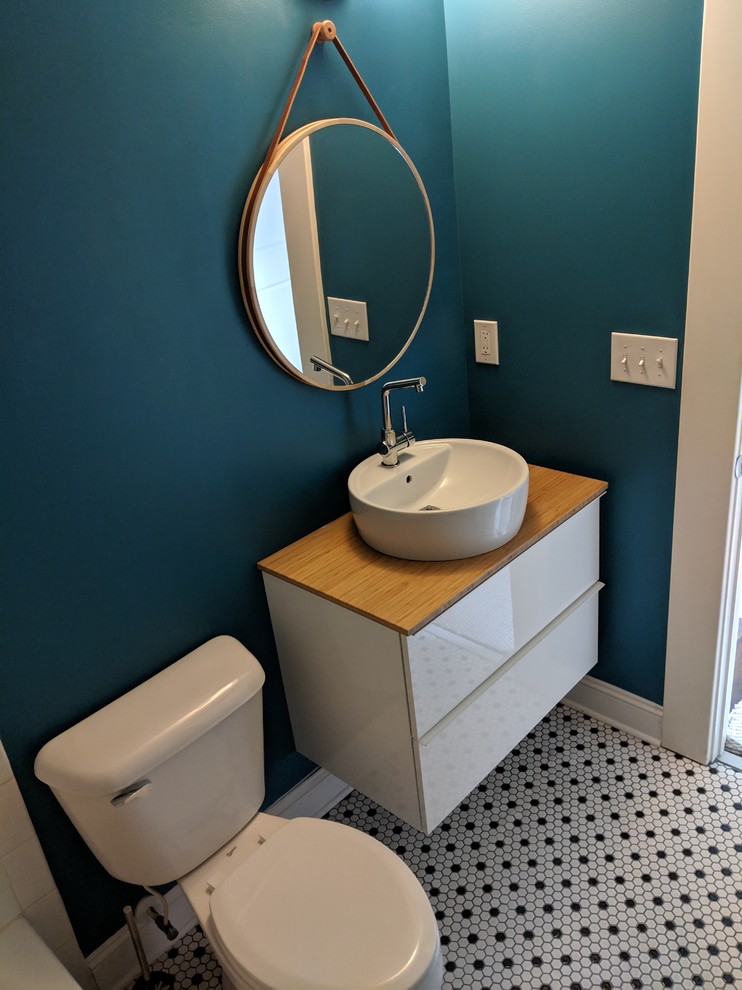 Mid-sized mid-century modern mosaic tile floor and multicolored floor powder room photo in Atlanta with flat-panel cabinets, white cabinets, a two-piece toilet, blue walls, a vessel sink, wood countertops and brown countertops