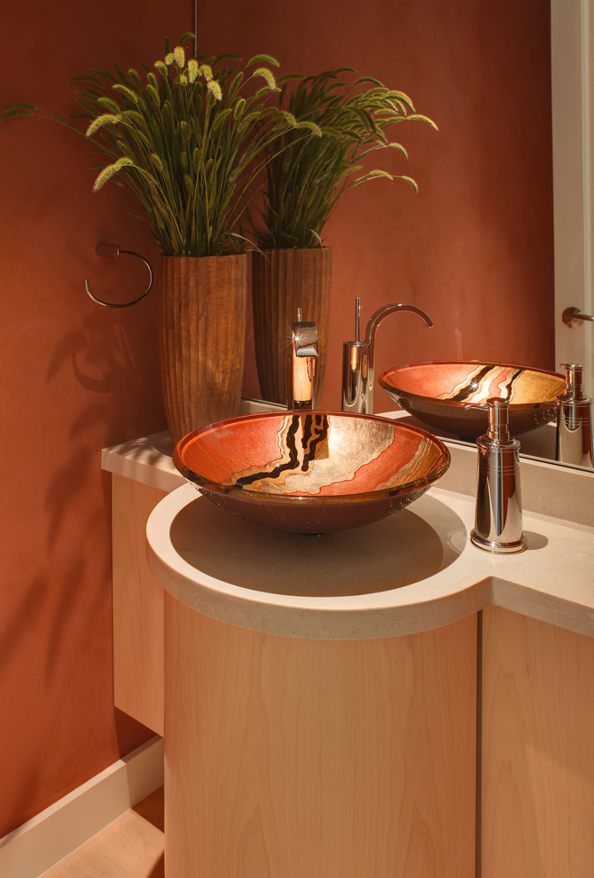 На фото: туалет в современном стиле с настольной раковиной, плоскими фасадами и светлыми деревянными фасадами с